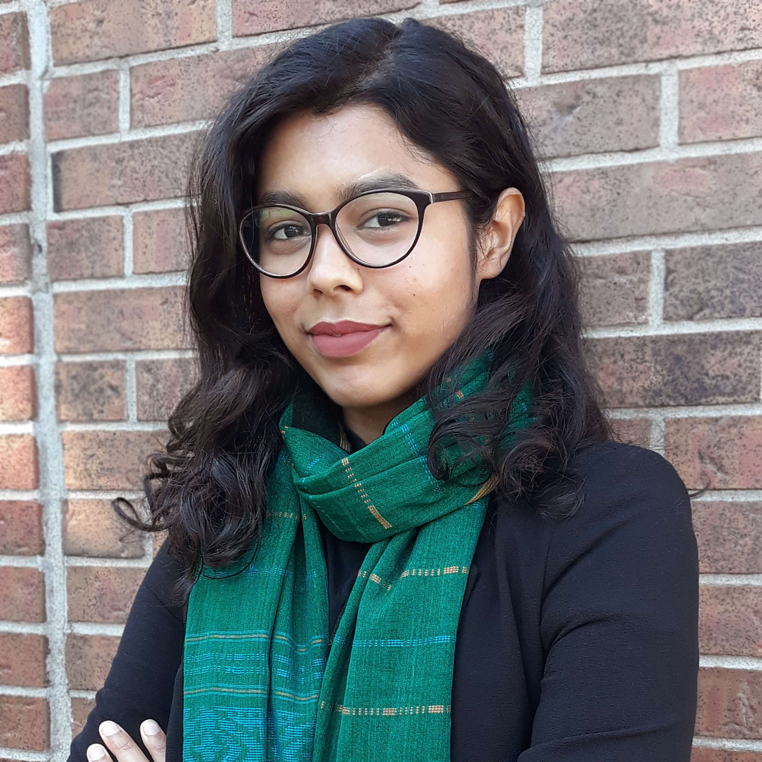 Headshot of Najeeba Ahmed, portrait style, positioned in front of a red brick wall.