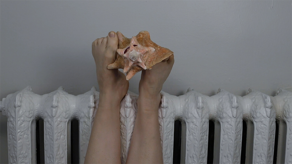 Feet holding up a shell against a radiator.