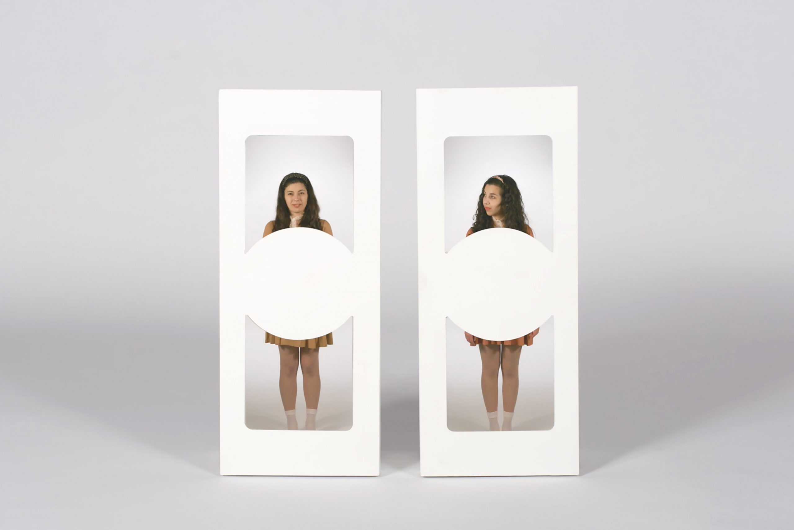 A still from Different Editions of the Same Kind by Alexia Kokozaki featuring two figures standing side by side in white, rectangular cutouts