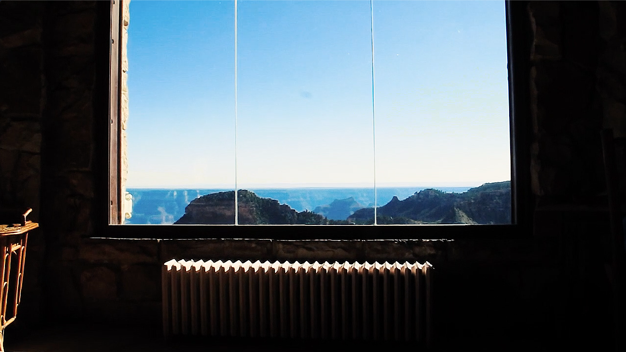 An image of distant mountains and blue skies taken through a large, clear window